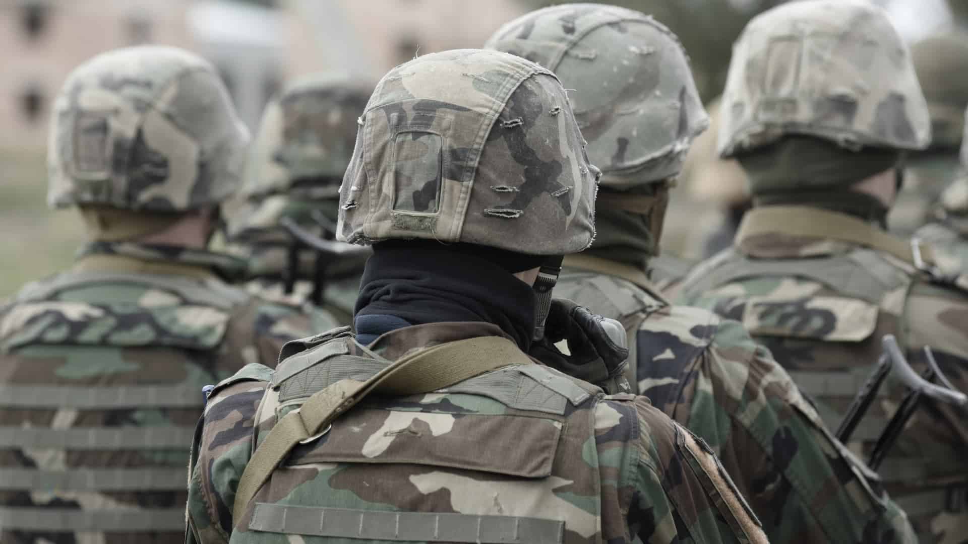 Soldiers dressed in camo facing away from camera